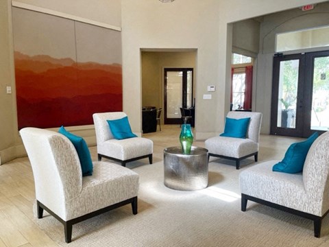 a living room with white chairs and a large painting on the wall
